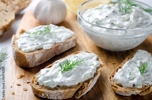 Quadro su tela Homemade greek tzatziki sauce in a glass bowl with sliced bread