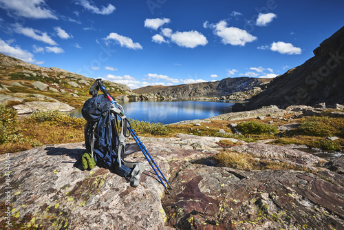 A backpack with hiking poles at a mountain lake
