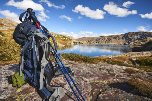 A backpack with hiking poles at a mountain lake