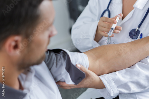 Фотография doctor gives an intramuscular injection in male arm