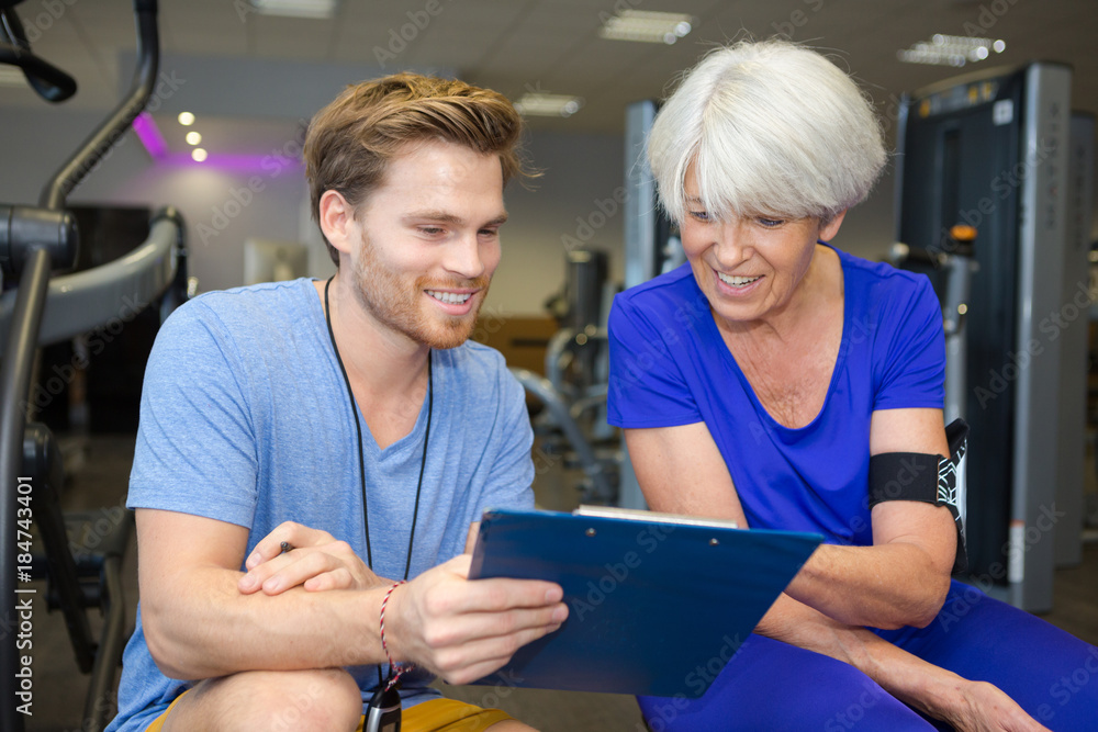 Obraz premium elderly lady working out with friendly young male trainer