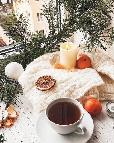 Winter breakfast. Tangerine and a cup of tea. Tree and the candles on the windowsill. Christmas morning 