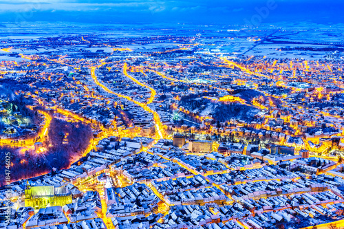 Brasov, Romania. Aerial view of the medieval city covered in snow with main square-Christmas market, Xmas Tree and old houses rooftops in Transylvania, Eastern Europe. photo