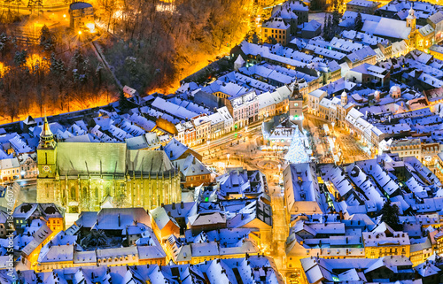 Brasov, Romania. Aerial view of the medieval city main square covered in snow with Christmas market and Xmas Tree, Transylvania, Eastern Europe.
