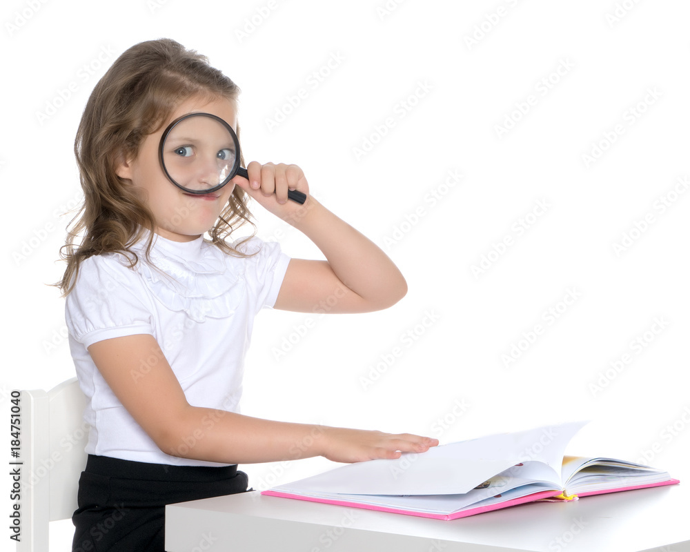 A little girl looks through a magnifying glass A little girl looks through a magnifying glass