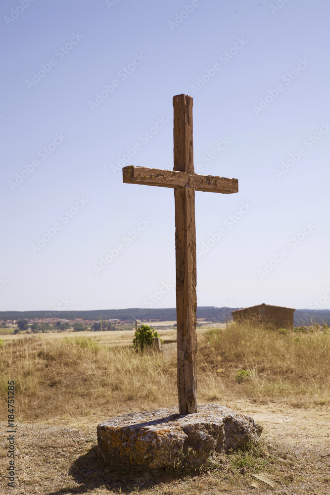 cruz símbolo religioso cristiano de madera en medio de un camino sujeta por  dos grandes piedras en un campo cerca de la carretera bajo el cielo azul  Stock Photo