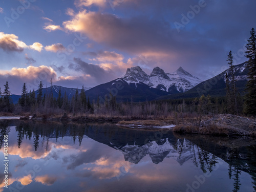 Sunrise view of the Three Sisters from a frozen Policemen s Creek along the Bow River outside Canmore  Alberta in winter.