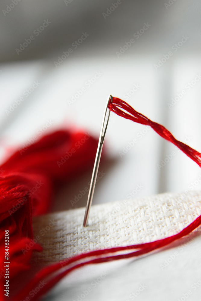 Needle in canvas with red thread for embroidery. Embroidery macro close up. View from above. Free copy space. Needle in canvas with red thread for embroidery. Embroidery macro close up. View from above. Free copy space.