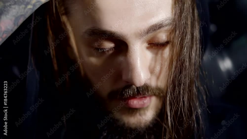 an adult man with a thick and long beard removes the hood and closes his eyes, he is in euphia an adult man with a thick and long beard removes the hood and closes his eyes, he is in euphia