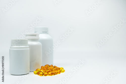 Yellow soft gelatin capsule pills with closed blank label bottle on white background with copy space, just add your own text. Use for advertise vitamin and supplement, health protection concept
