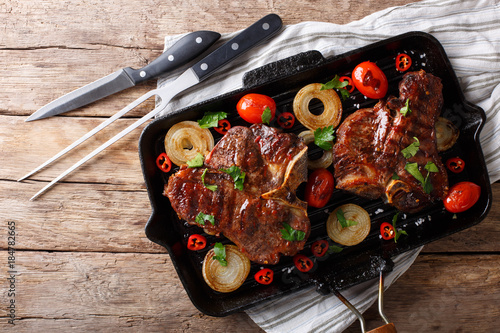 Delicious T Bone steak with grilled vegetables on the grill pan close-up. Horizontal top view