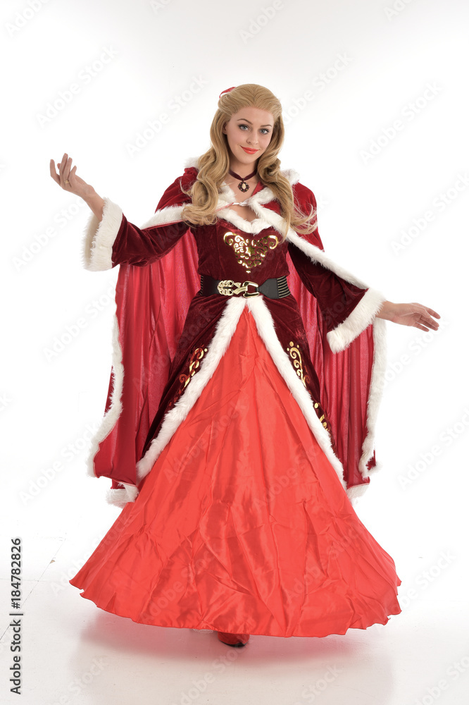full length portrait of pretty blonde lady wearing red and white christmas inspired costume gown, standing pose on white background. full length portrait of pretty blonde lady wearing red and white christmas inspired costume gown, standing pose on white background.