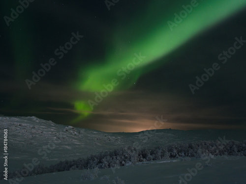Northern lights, aurora over hills and tundra in the winter. © Moroshka