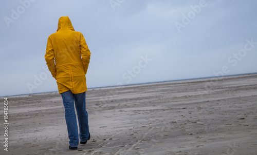 Photos Mann in gelbem Regenmantel an einsamen Strand
