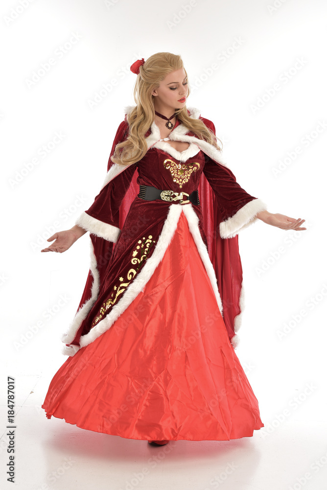 full length portrait of pretty blonde lady wearing red and white christmas inspired costume gown, standing pose on white background.