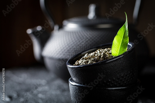 Closeup of leaf green tea in teacup on black rock