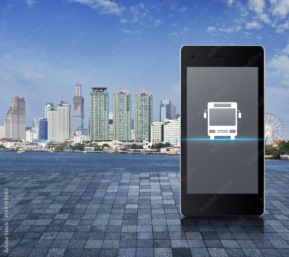 Bus flat icon button on modern smart phone screen on stone tile floor over city tower, river and blue sky, Business transportation service concept Bus flat icon button on modern smart phone screen on stone tile floor over city tower, river and blue sky, Business transportation service concept