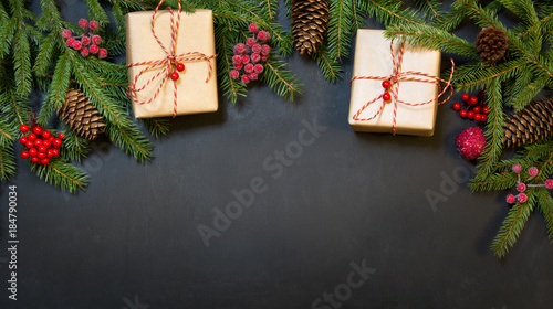 Christmas holiday background - tree, gifts, holly berries and decoration on a black chackboard. Holiday card with copy space. View from above. photo