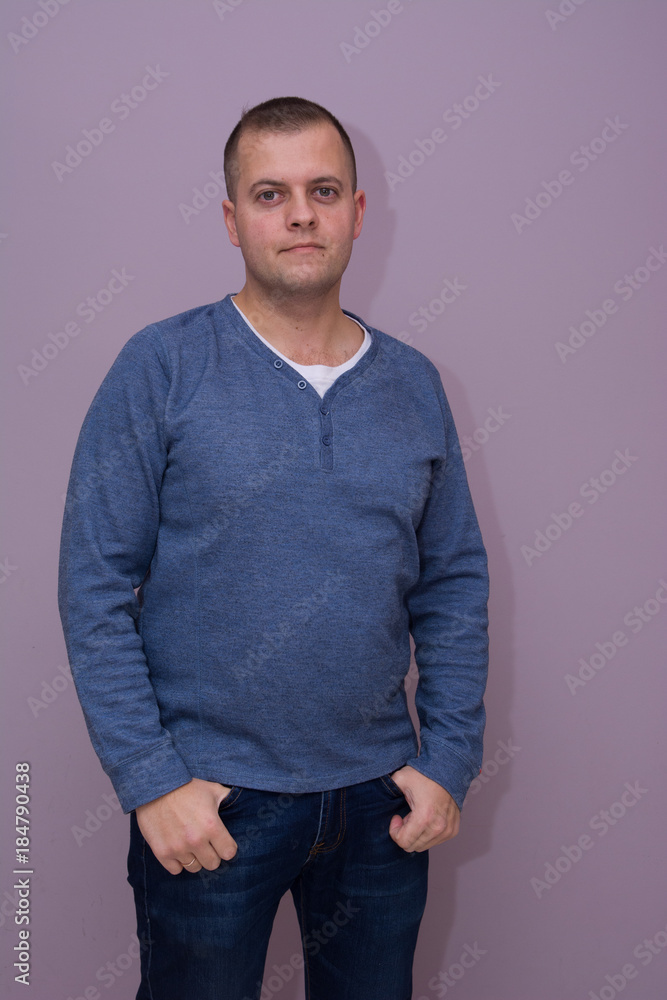 Fashionable handsome fat man with beard poses with crossed arms in studio near wall Fashionable handsome fat man with beard poses with crossed arms in studio near wall