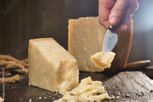 macro of a middle aged chef cutting cheese with knife on wooden board on restaurant kitchen table (extra close up) photo