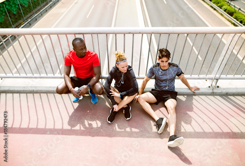 Young runners in the city resting on a bridge.