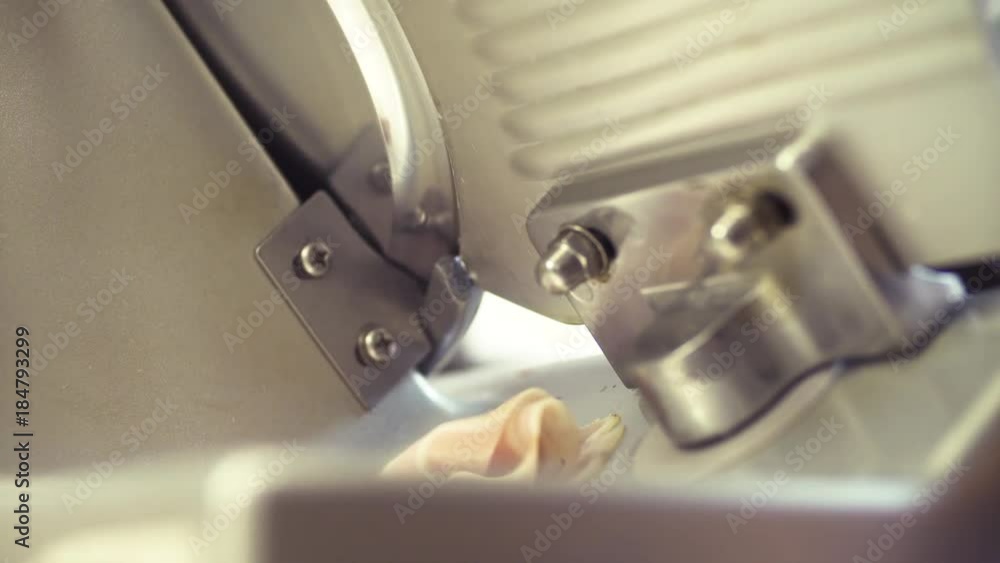 Cooking in the restaurant. Close up. Slice machine in commercial kitchen cutting ham Cooking in the restaurant. Close up. Slice machine in commercial kitchen cutting ham