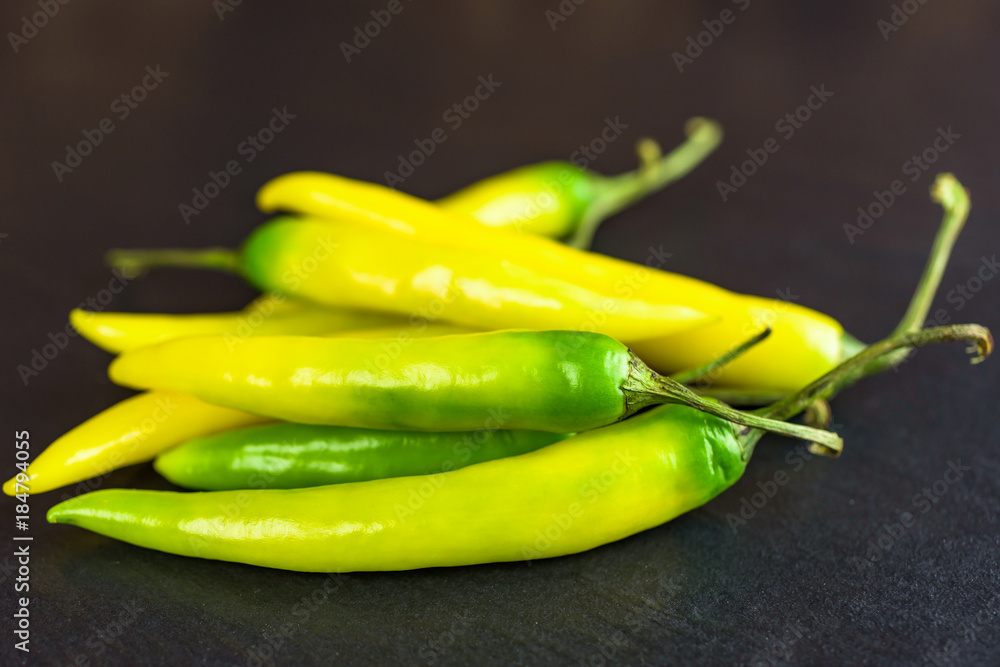 Pile of yellow and green peppers on black stone slab. Pile of yellow and green peppers on black stone slab.