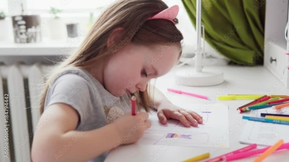 Cute little girl is sitting at the table and drawing Cute little girl is sitting at the table and drawing