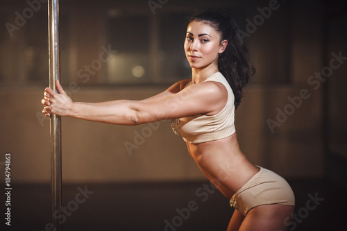 Pole dance. Slim woman in sexy lingerie posing with pylon.