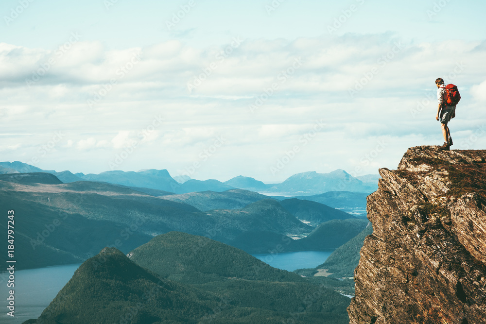 Man explorer standing on cliff alone mountain summit over fjord Norway landscape Travel Lifestyle success motivation concept adventure active vacations outdoor - obrazy, fototapety, plakaty 
