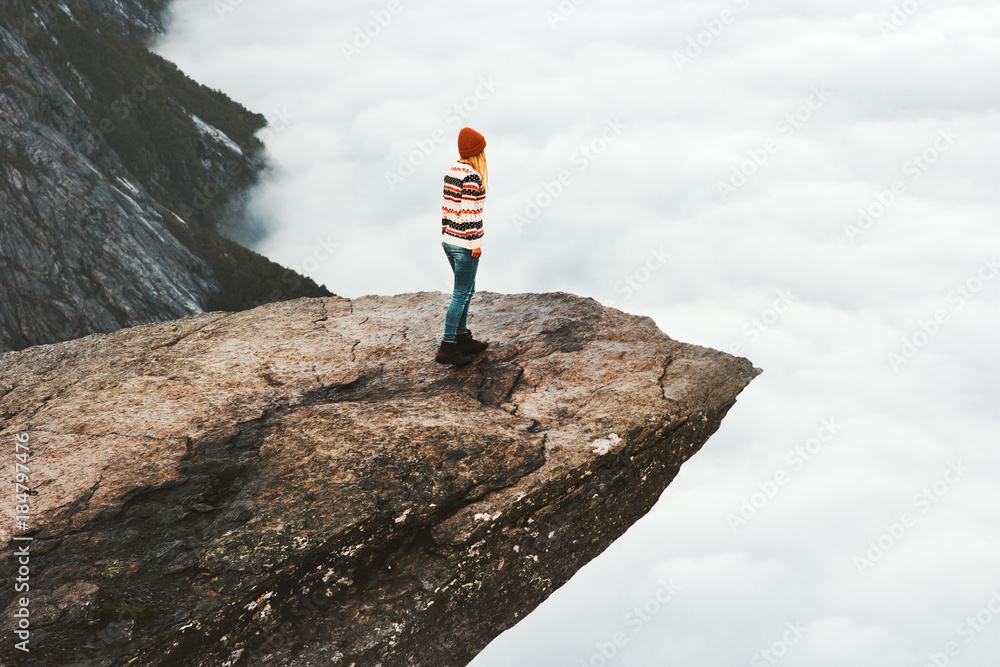 Woman explorer walking on Trolltunga rocky cliff in Norway mountains Travel Lifestyle adventure concept extreme vacations outdoor above clouds - obrazy, fototapety, plakaty 
