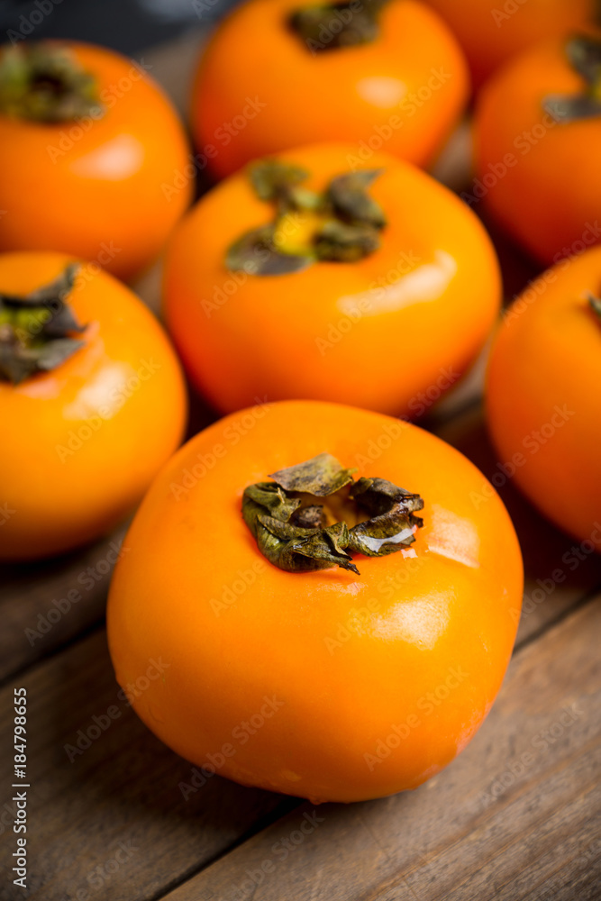 Fresh persimmon fruit on wooden table. Selective focus. Shallow depth of field. Fresh persimmon fruit on wooden table. Selective focus. Shallow depth of field.