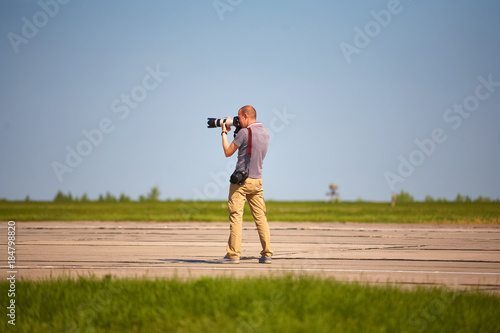 A photographer with two cameras in a summer field takes pictures of nature.