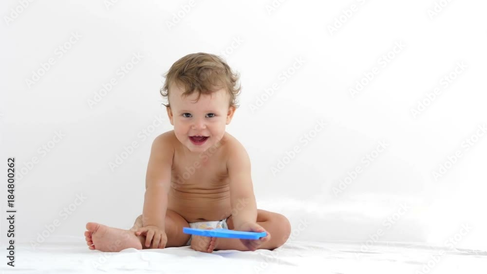 Studio shot of an adorable little baby boy in white diapers smiling and looking up on white background.
Studio shot of an adorable little baby boy in white diapers smiling and looking up on white background.