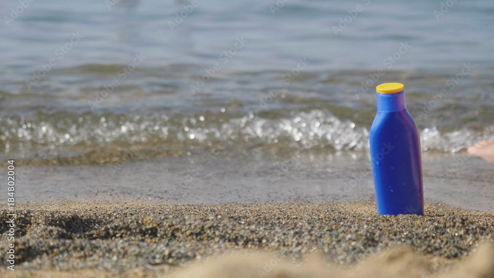 A jar of sunscreen on the beach near the sea A jar of sunscreen on the beach near the sea