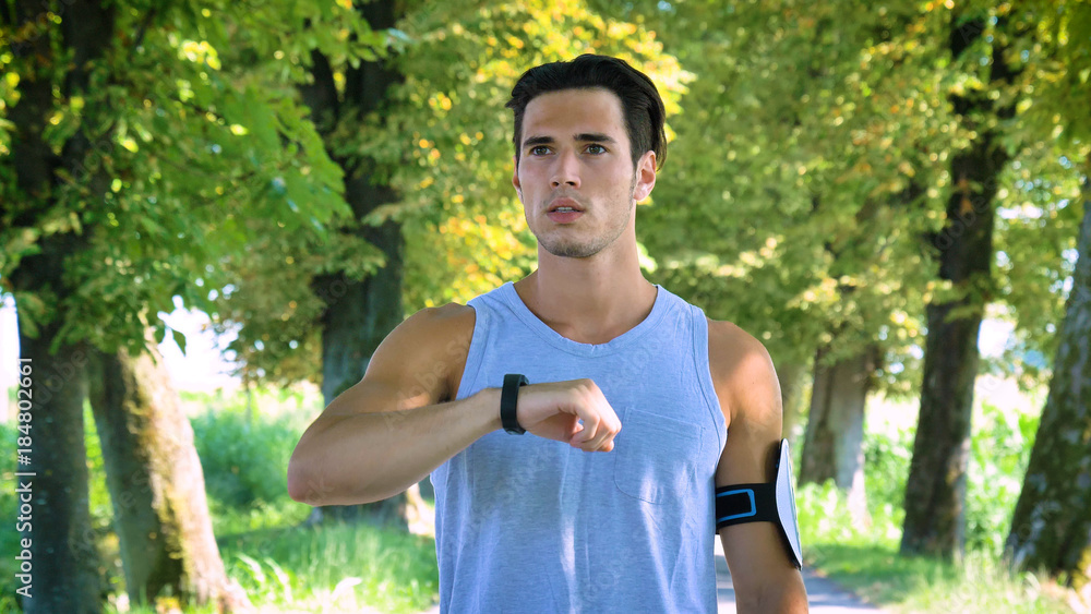 Handsome young guy sportsman checking the time on his clock. Concept: love sports, healthy lifestyle, be beautiful, muscles, happy, burn calories Handsome young guy sportsman checking the time on his clock. Concept: love sports, healthy lifestyle, be beautiful, muscles, happy, burn calories