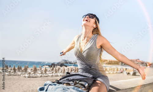 Young woman travel blogger listening music at Los Cristianos beach promenade - Wanderlust vacation concept with adventure girl tourist wanderer on trip excursion in Tenerife - Bright sunshine filter