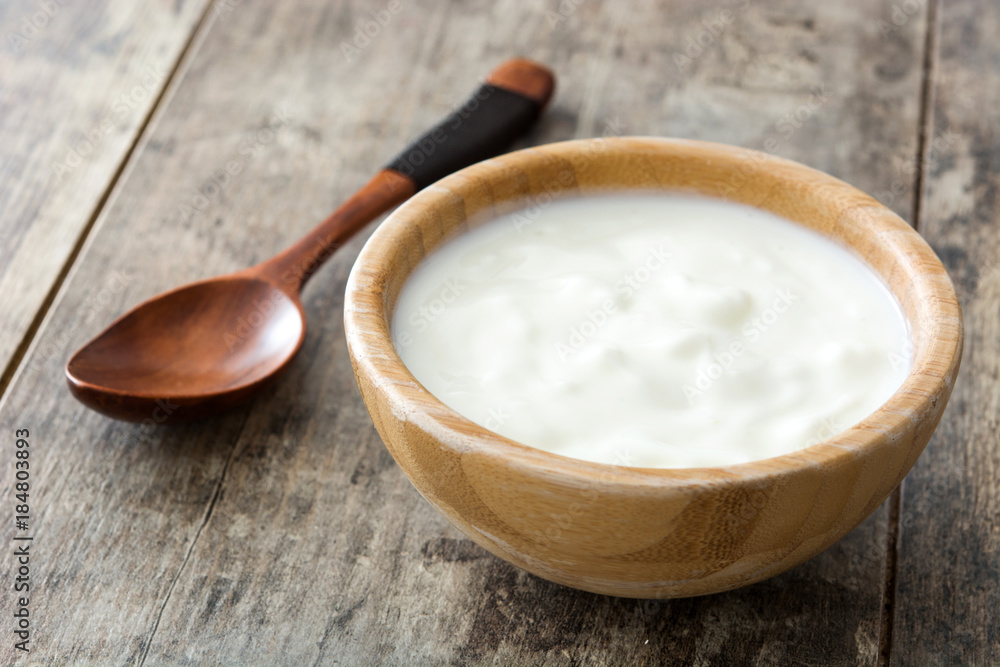 Natural yogurt in wooden bowl on wooden table Natural yogurt in wooden bowl on wooden table