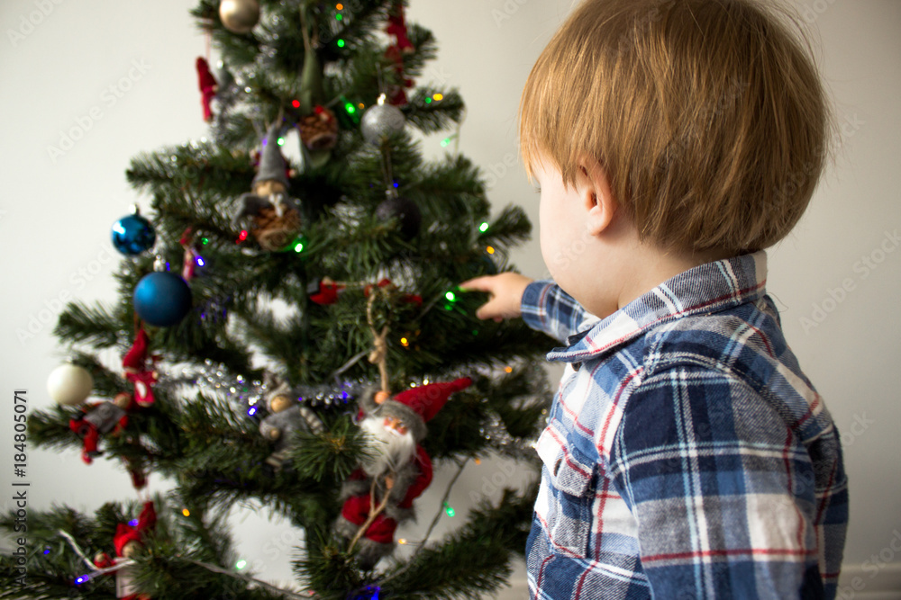 cute little boy playing near Christmas tree. beautiful and cute toddler boy sits near Christmas tree. holidays cute little boy playing near Christmas tree. beautiful and cute toddler boy sits near Christmas tree. holidays