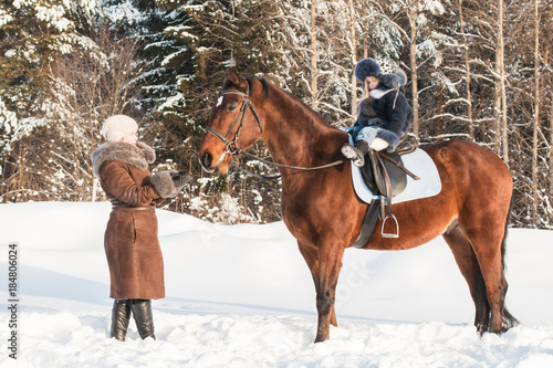 Small girl and mom near horse in a winter