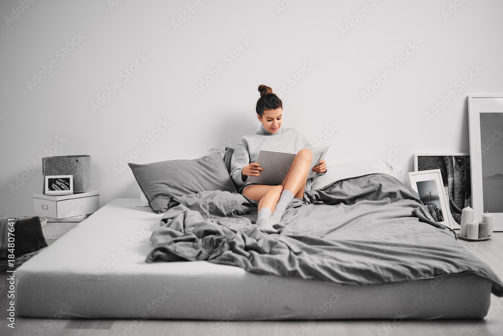 Woman sitting on bed in the morning and reading book