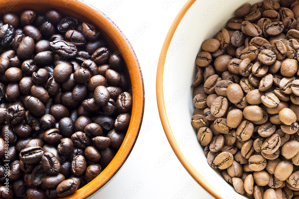 Fototapeta premium two different types of coffee beans with different roast in cups on a white background
