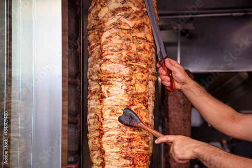 Canvas Print Gyros, doner. Man's hands holding a knife, cutting slices