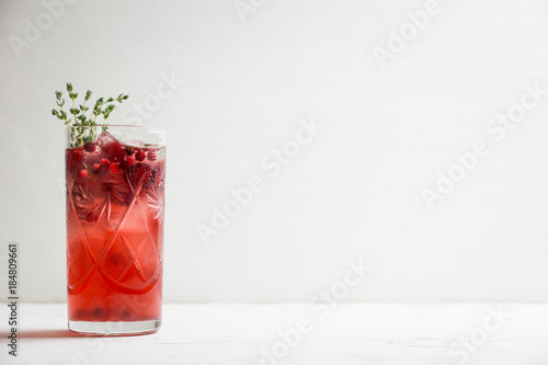 Christmas cocktail with berries and thyme on the rustic background. Selective focus.