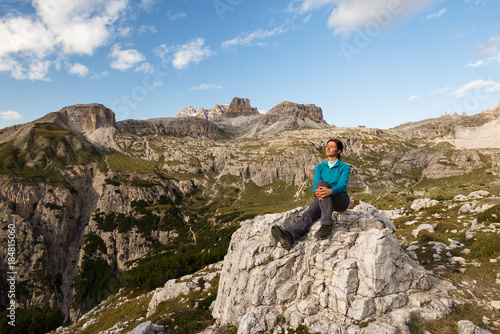 Young female is enjoying sunshine in Dolomite mountains, Italy