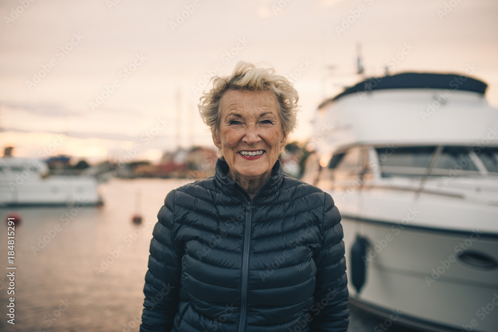 Portrait of happy senior woman standing at harbor during sunset Portrait of happy senior woman standing at harbor during sunset