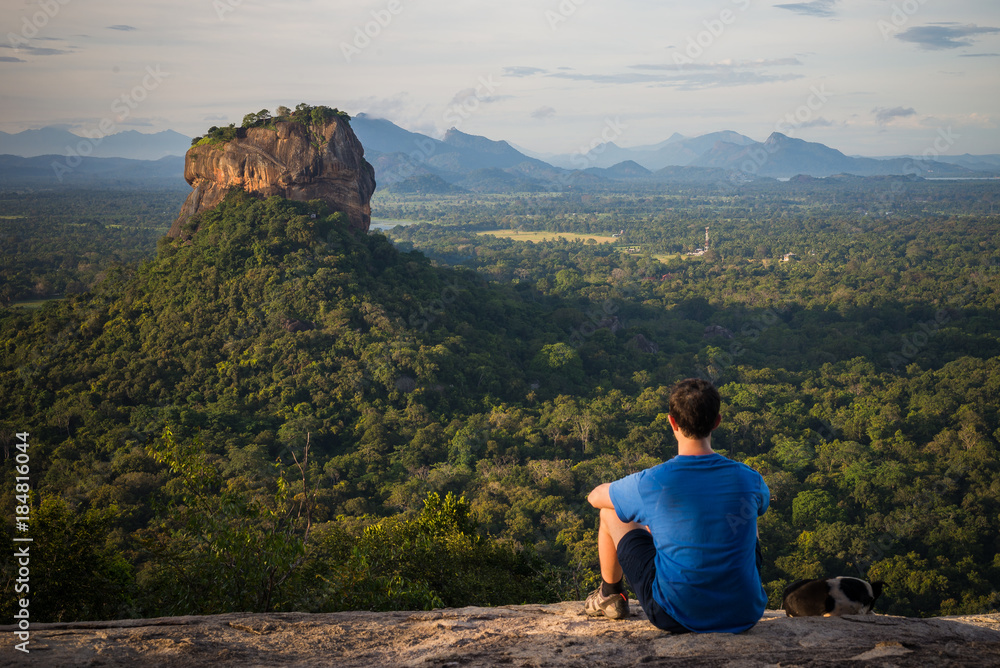 Young man looking at the Sigiriya Rock from Pidurangala rock in Sri Lanka