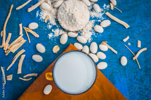 Close up of two ayurvedic herbs i.e. cowhage,kuanch,Mucuna pruriens and satavari,Asparagus racemosus and milk glass. photo