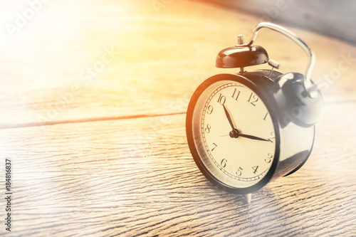 wake up black old retro alarm clock on wooden texture floor in morning light