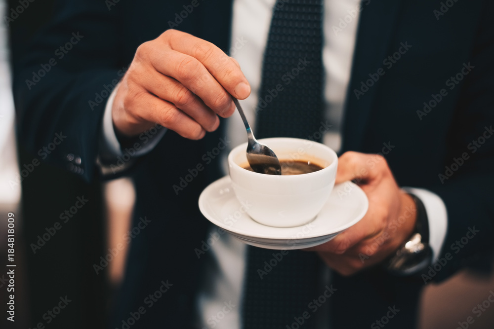 Midsection of businessman stirring coffee from spoon in cafe Midsection of businessman stirring coffee from spoon in cafe